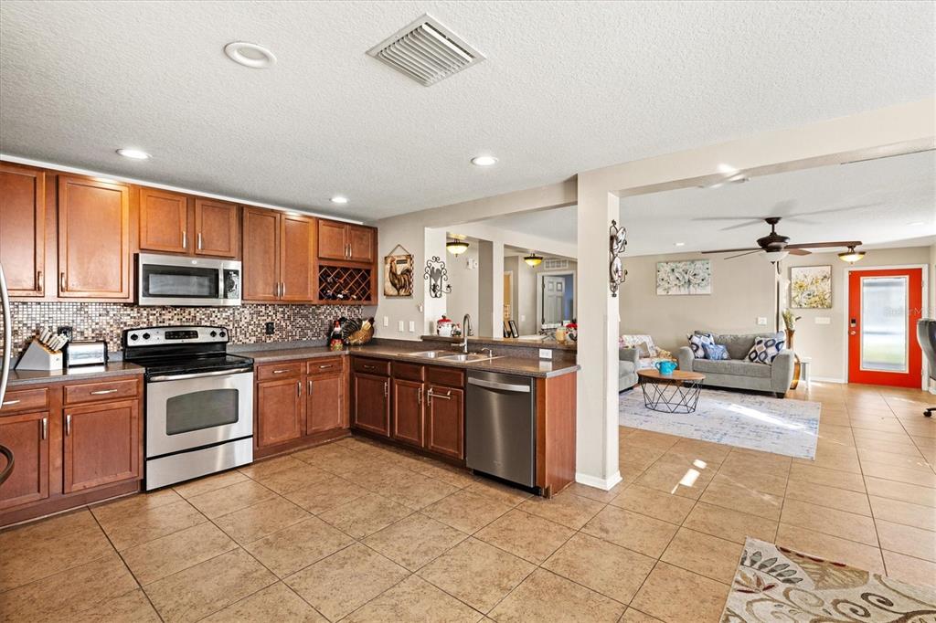 5213 Moon Shell Drive Apollo Beach, FL 33572 - Photo 16 of 69 a kitchen with stainless steel appliances granite countertop a stove top oven a sink dishwasher a dining table and chairs with wooden floor