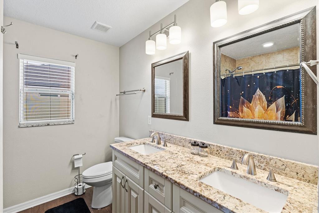 5213 Moon Shell Drive Apollo Beach, FL 33572 - Photo 21 of 69 a bathroom with a granite countertop toilet a sink and a mirror
