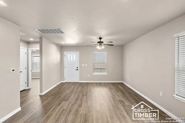 a view of an empty room with wooden floor and a window