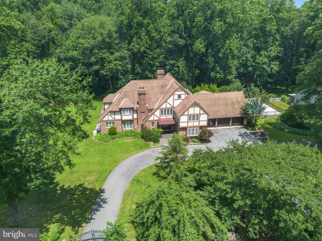 an aerial view of a house with a big yard and large trees