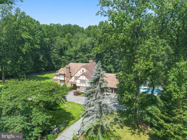 an aerial view of residential house with outdoor space and trees all around