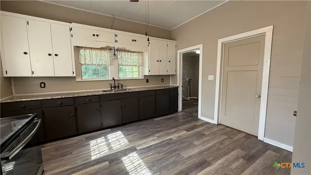 a kitchen with stainless steel appliances granite countertop a sink and cabinets with wooden floor