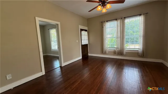 an empty room with wooden floor and a ceiling fan