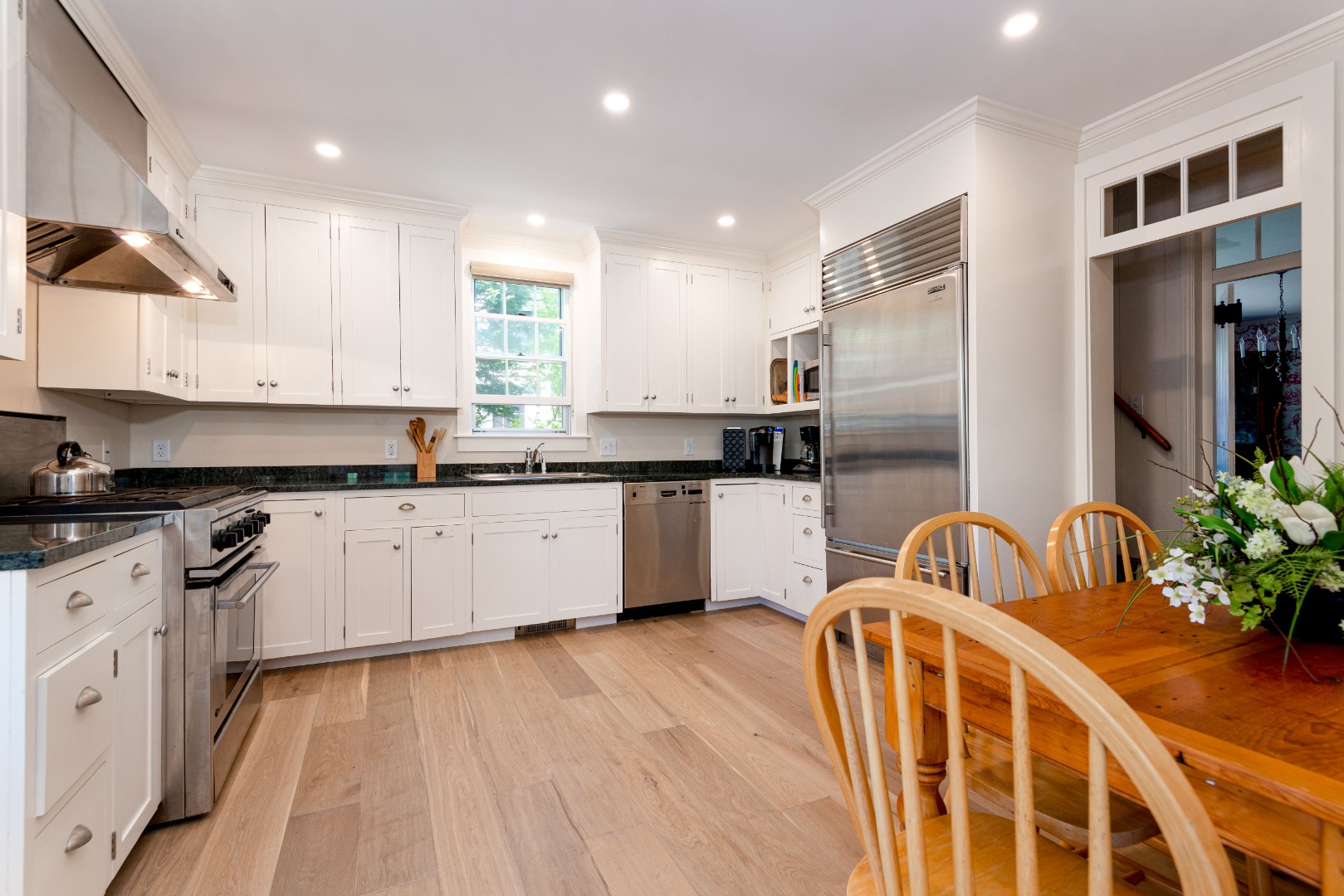 24 Cliff Road Nantucket, MA 02554 - Photo 31 of 44 a kitchen with stainless steel appliances kitchen island granite countertop a sink a stove a refrigerator cabinets and a dining table with wooden floor