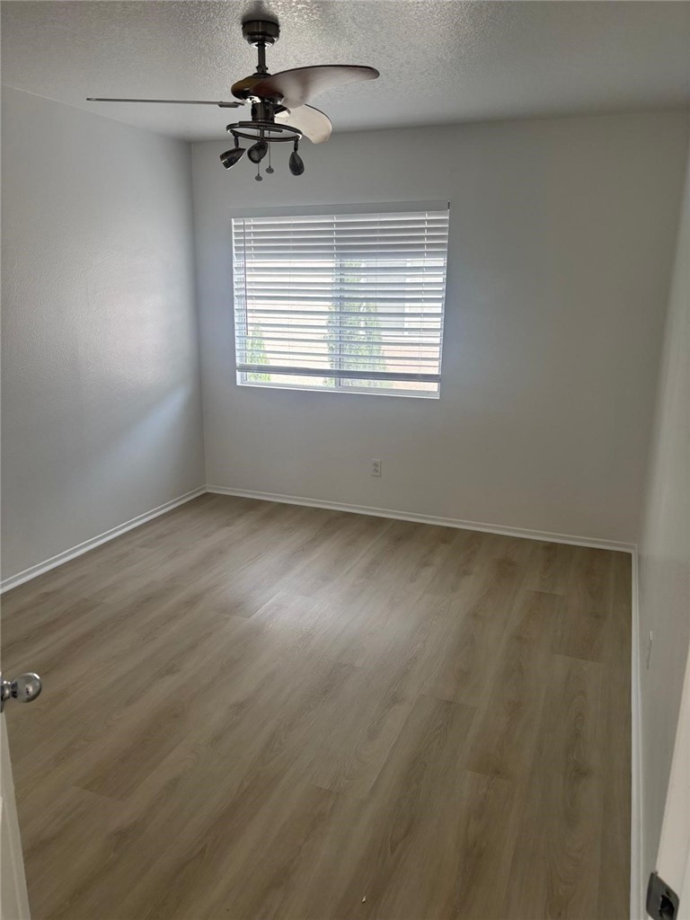 731 Raphael Circle Corona, CA 92882 - Photo 22 of 28 an empty room with wooden floor ceiling fan and windows