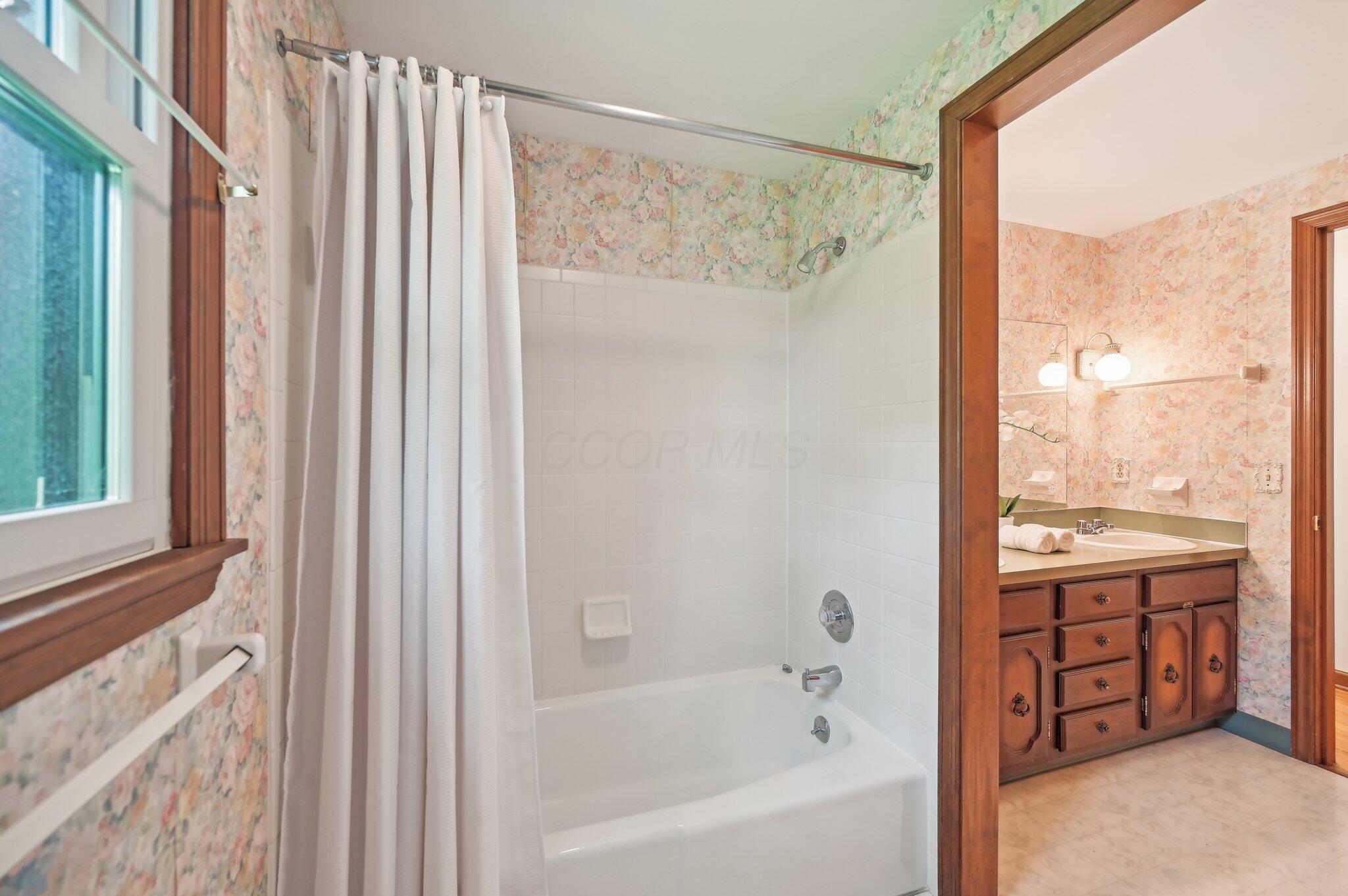 5917 Rocky Rill Road Columbus, OH 43235 - Photo 32 of 47 Tub/Shower Combo (Full Bathroom)
The tub/shower combo sits in a tiled alcove with a classic white surround and matching fixtures. A nearby window brings in natural light, while the floral wallpaper continues for a cohesive feel.