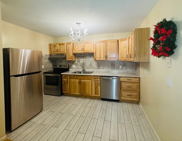 a kitchen with stainless steel appliances granite countertop a sink cabinets and wooden floor
