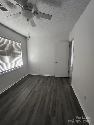an empty room with wooden floor cabinet and windows