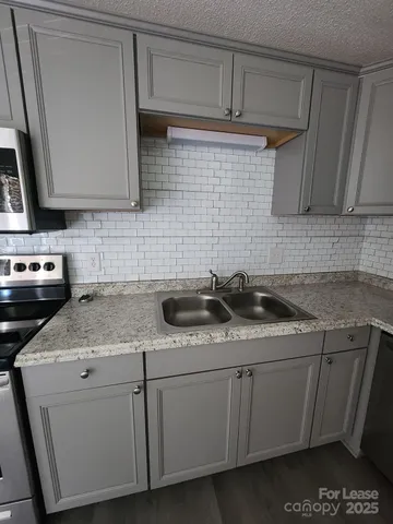 a kitchen with stainless steel appliances granite countertop a sink a stove and cabinets