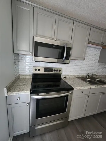 a kitchen with granite countertop white cabinets and stainless steel appliances