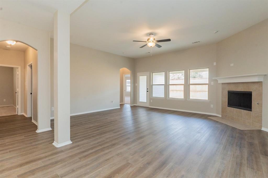 4313 Summer Star Lane Fort Worth, TX 76244 - Photo 11 of 26 Unfurnished living room with arched walkways, a ceiling fan, wood finished floors, and a fireplace