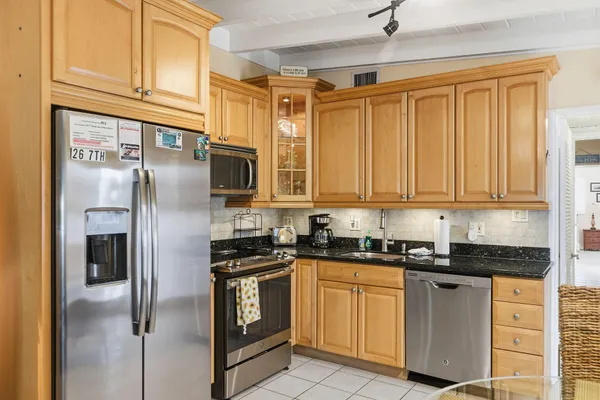 a kitchen with stainless steel appliances granite countertop a refrigerator a sink a stove and white cabinets