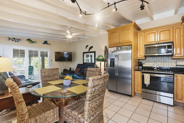 a kitchen with stainless steel appliances granite countertop a refrigerator a stove a dining table and chairs with wooden floor