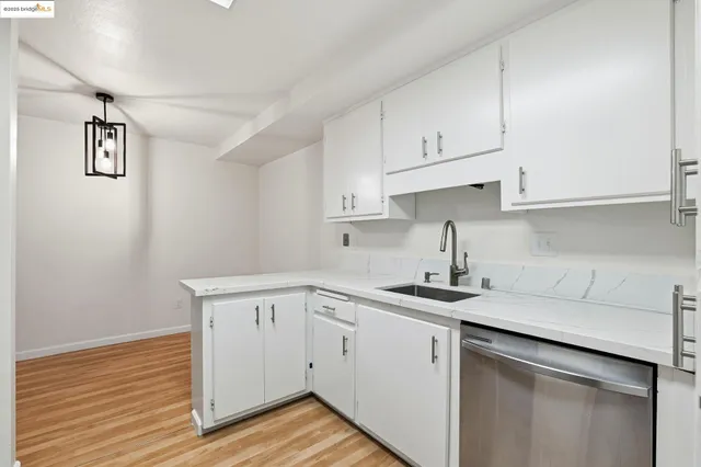 a kitchen with cabinets stainless steel appliances and wooden floor