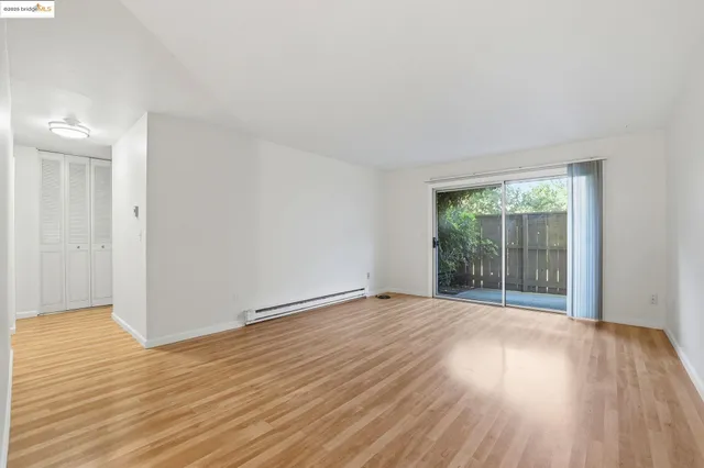 a view of an empty room with wooden floor and a window