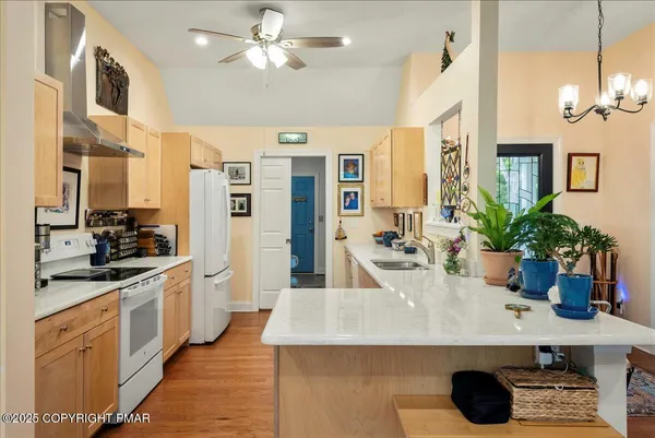 a kitchen with stainless steel appliances kitchen island granite countertop a sink a stove and a wooden floors