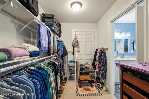 a view of walk in closet with clothes and shoes
