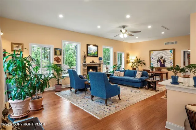 a living room with furniture potted plant floor to ceiling windows and a fireplace