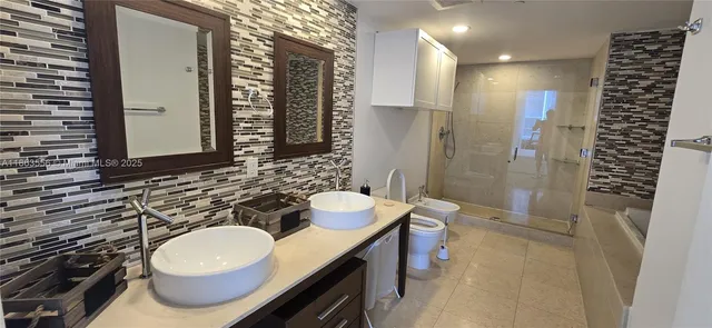 a bathroom with a double vanity sink toilet mirror and shower
