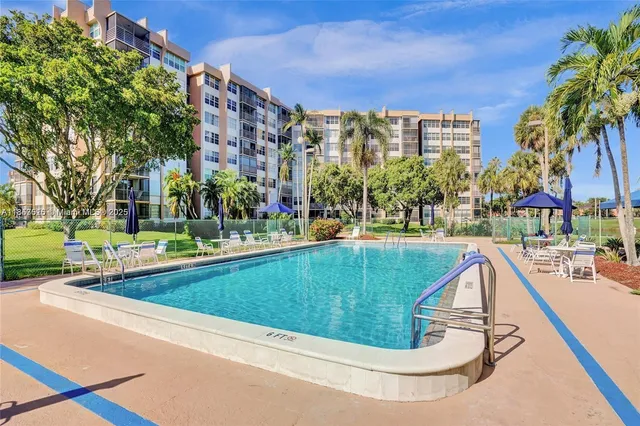 a view of swimming pool with outdoor seating and trees in the background