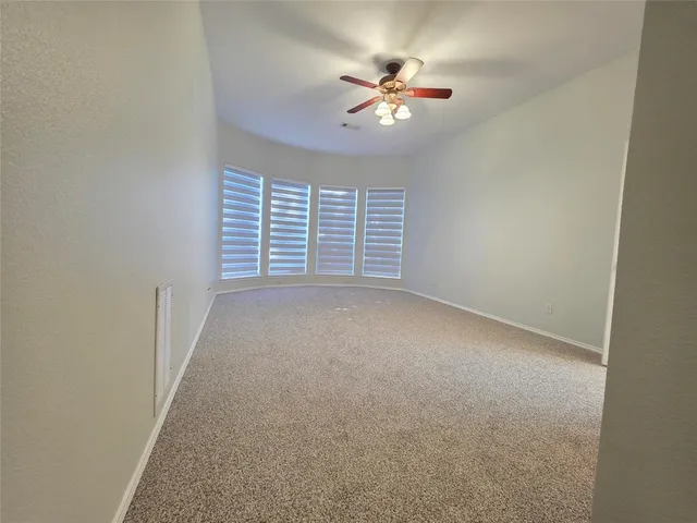 a view of an empty room with a chandelier fan
