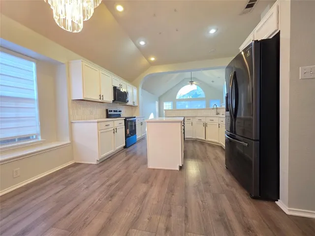 a kitchen with a refrigerator a stove top oven a sink dishwasher and a refrigerator with wooden floor