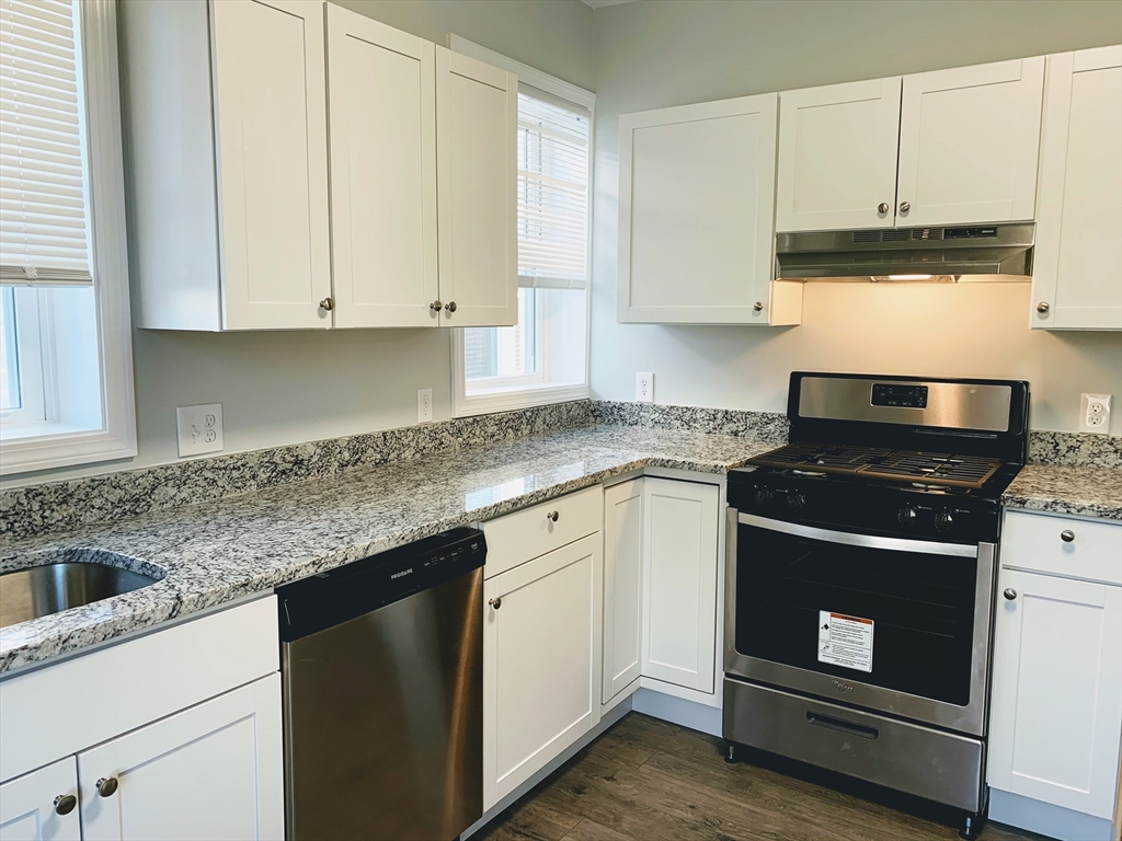 a kitchen with granite countertop white cabinets and black appliances
