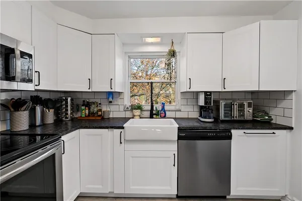 a kitchen with stainless steel appliances granite countertop a stove and white cabinets