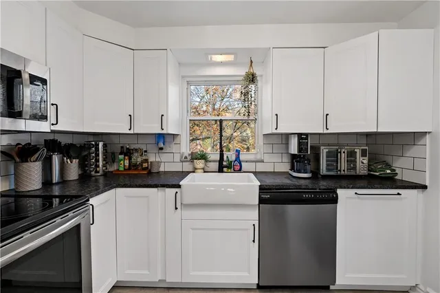 a kitchen with stainless steel appliances granite countertop a stove and white cabinets
