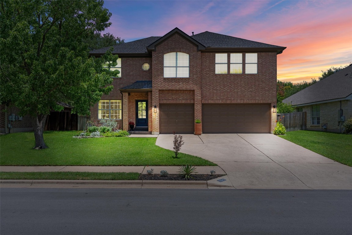 Traditional-style home featuring an attached garage, concrete driveway, and brick siding