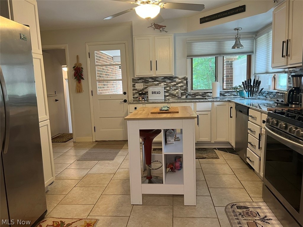 759 Truesdale Road Youngstown, OH 44511 - Photo 10 of 37 Kitchen with white cabinetry, ceiling fan, decorative backsplash, appliances with stainless steel finishes, and light tile patterned floors