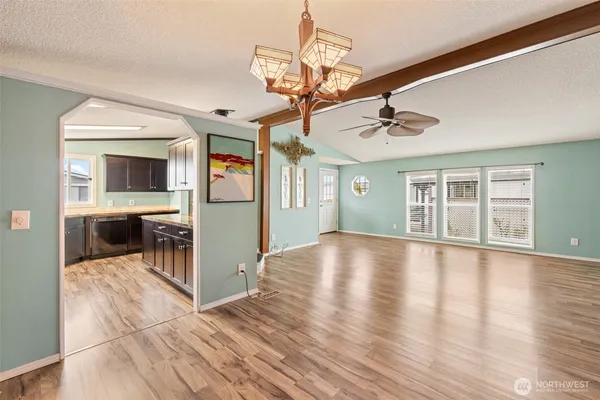 a view of an empty room with wooden floor and a kitchen