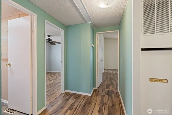 a view of a hallway with wooden floor and a bathroom