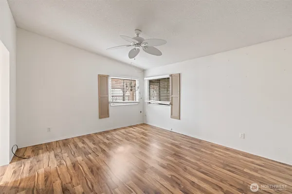 an empty room with windows and ceiling fan