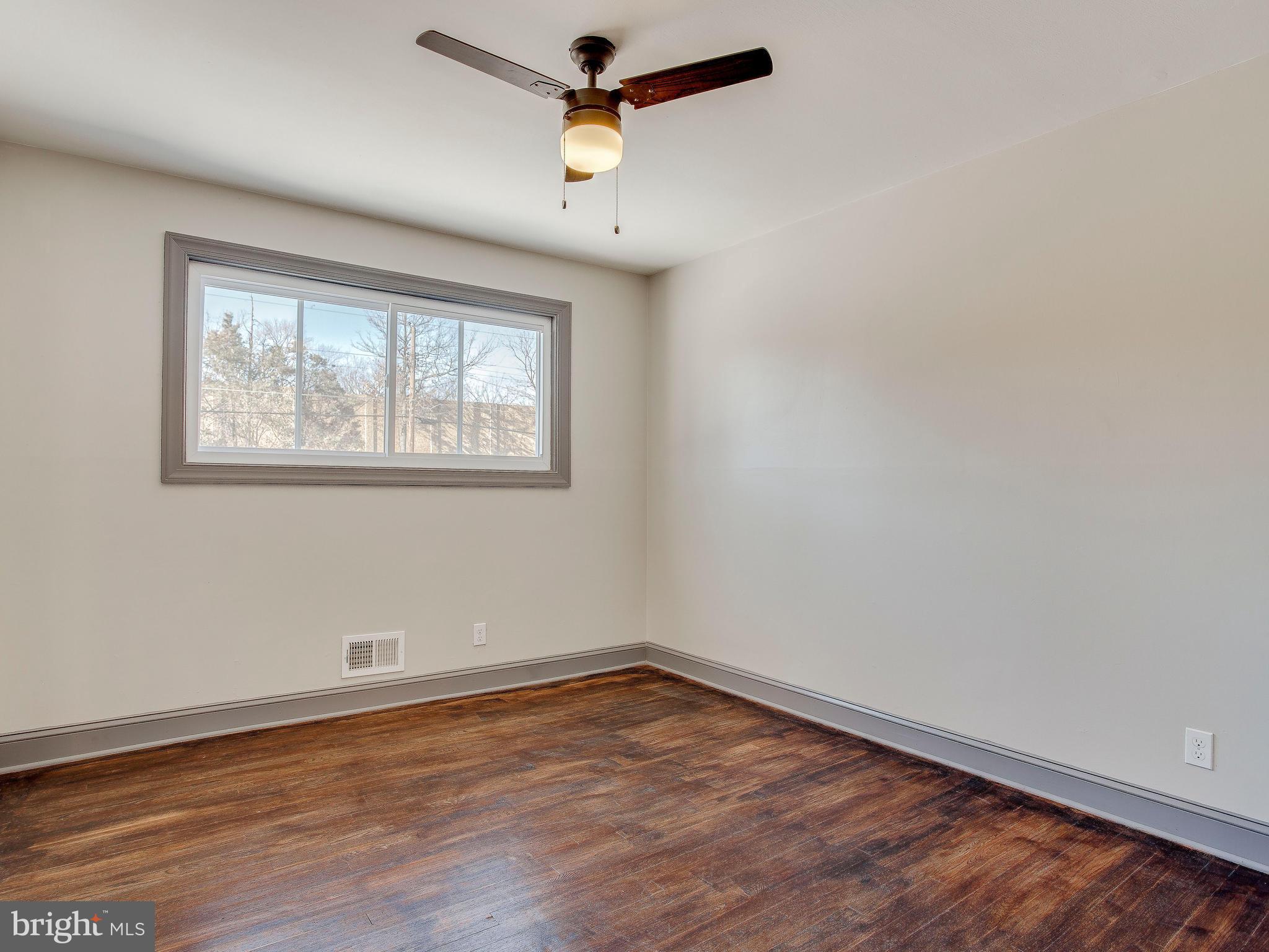 3112 Fairview Road Baltimore, MD 21207 - Photo 22 of 28 an empty room with wooden floor ceiling fan and windows