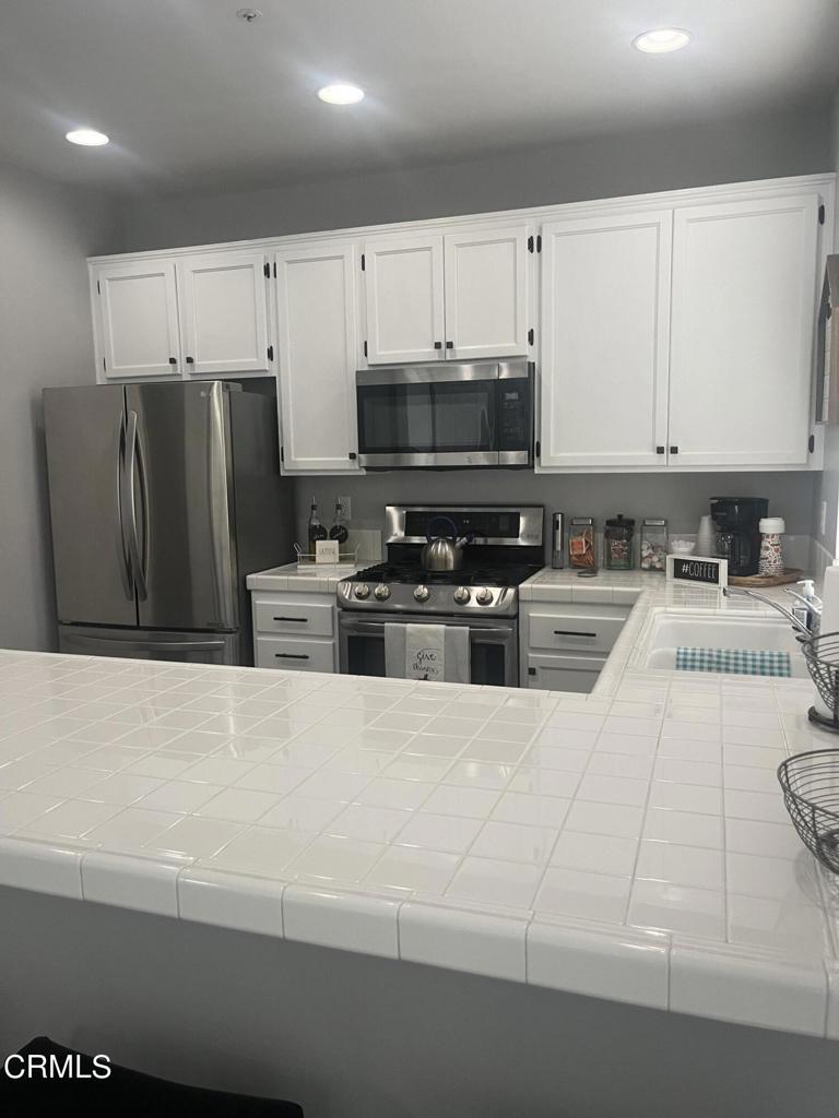 1027 Corte Primavera Oxnard, CA 93030 - Photo 12 of 23 a kitchen with stainless steel appliances a refrigerator a stove a microwave and cabinets