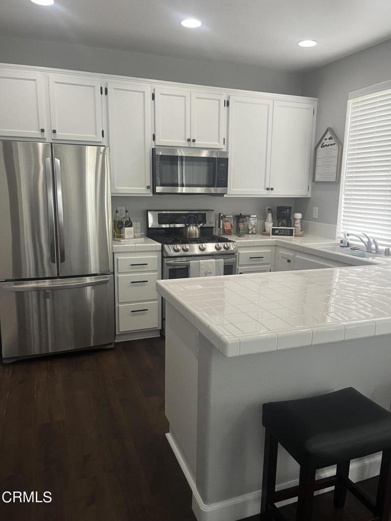 1027 Corte Primavera Oxnard, CA 93030 - Photo 10 of 23 a kitchen with a sink a microwave a refrigerator and white cabinets