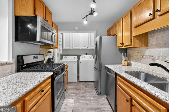 a kitchen with stainless steel appliances granite countertop a sink a stove and a refrigerator