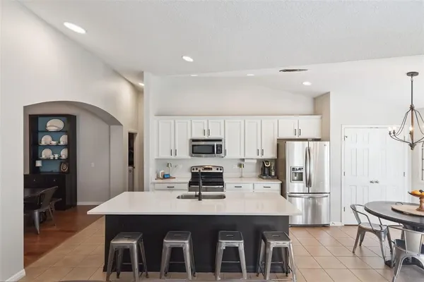 a kitchen with stainless steel appliances a stove a sink a refrigerator and white cabinets with wooden floor