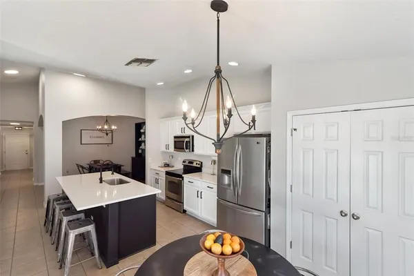 a kitchen with refrigerator a sink and chairs