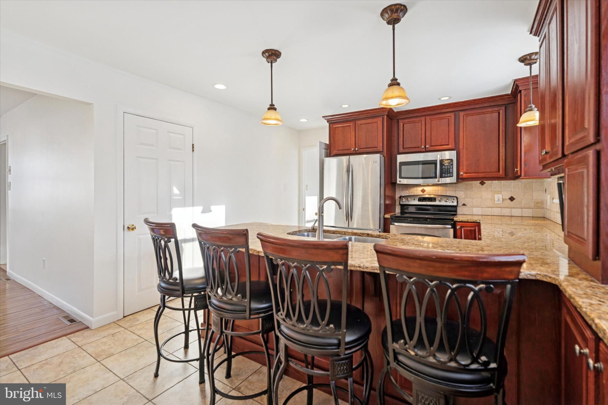 725 Springdell Road King of Prussia, PA 19406 - Photo 14 of 29 a kitchen with stainless steel appliances granite countertop a stove a sink dishwasher and a dining table with wooden cabinet