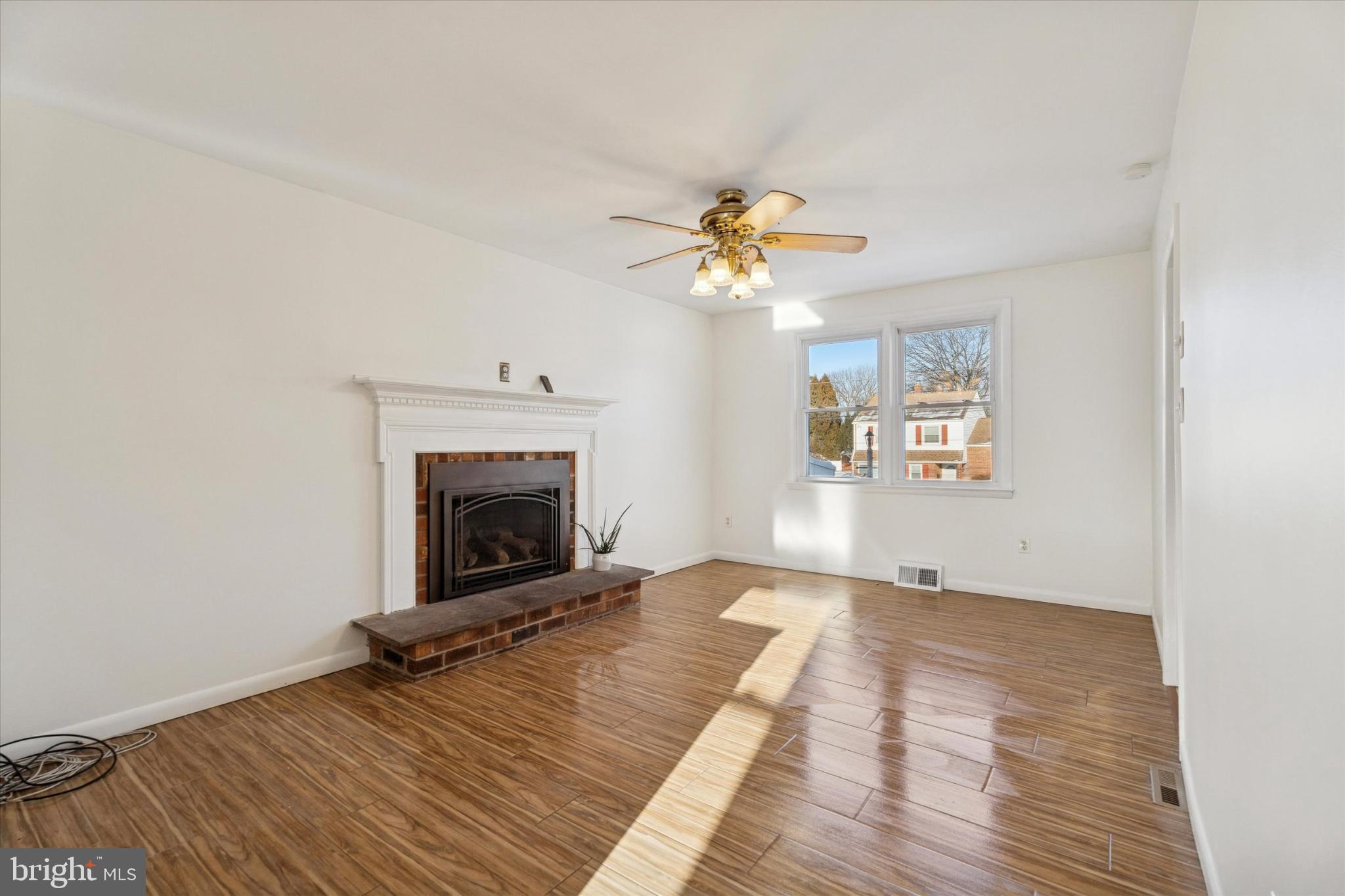 725 Springdell Road King of Prussia, PA 19406 - Photo 8 of 29 a view of a livingroom with a fireplace a ceiling fan and wooden floor