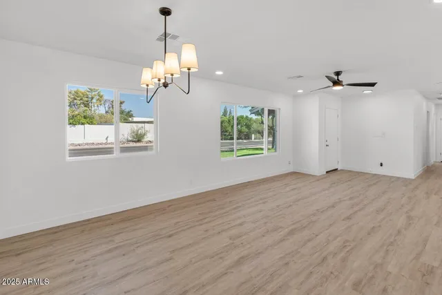 a view of a room with wooden floor ceiling fan and windows