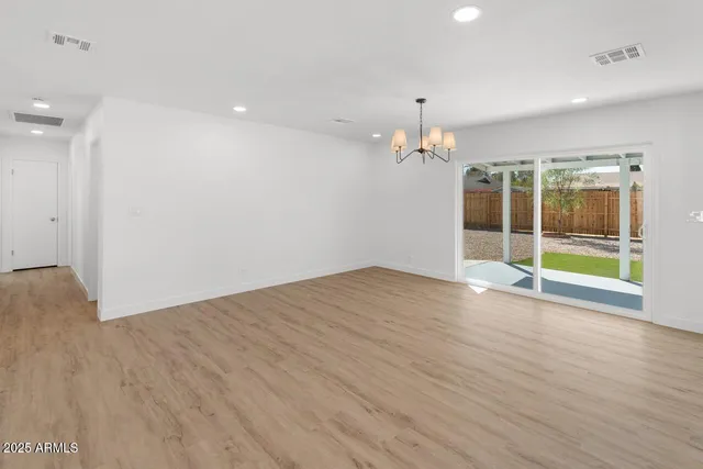 an empty room with wooden floor and chandelier
