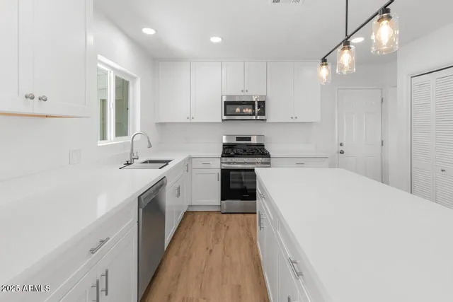 a kitchen with stainless steel appliances a white stove top oven sink and cabinets