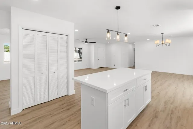 a large white kitchen with a sink a refrigerator and wooden floor