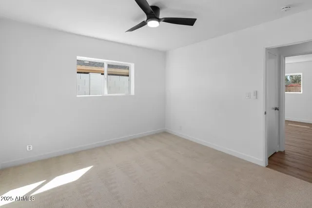 an empty room with a ceiling fan and a window