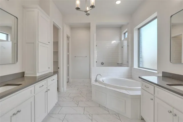 a spacious bathroom with a granite countertop tub sink shower and mirror