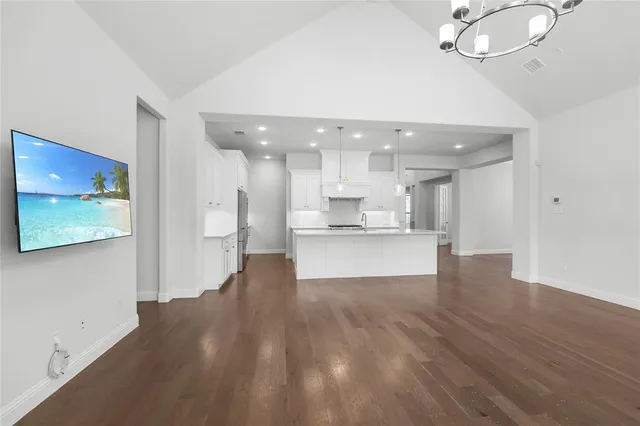 an empty room with wooden floor chandelier and glass door