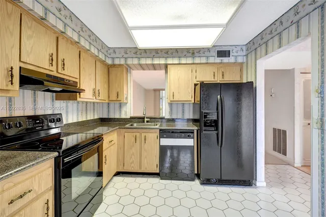a kitchen with granite countertop a stove a refrigerator and a sink